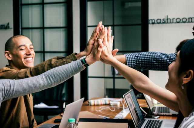 Picture of peoples hands high fiving each other in an office