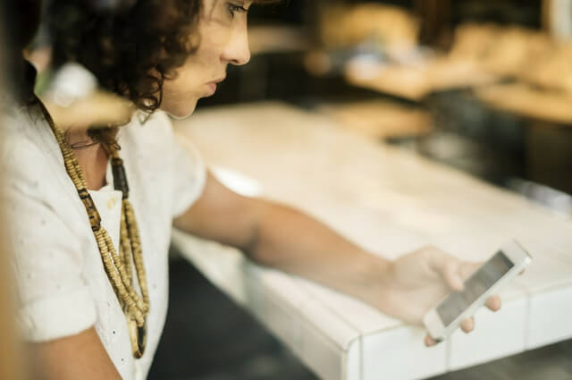 A picture of a lady starring stressed at her phone as her work and life is out of balance.