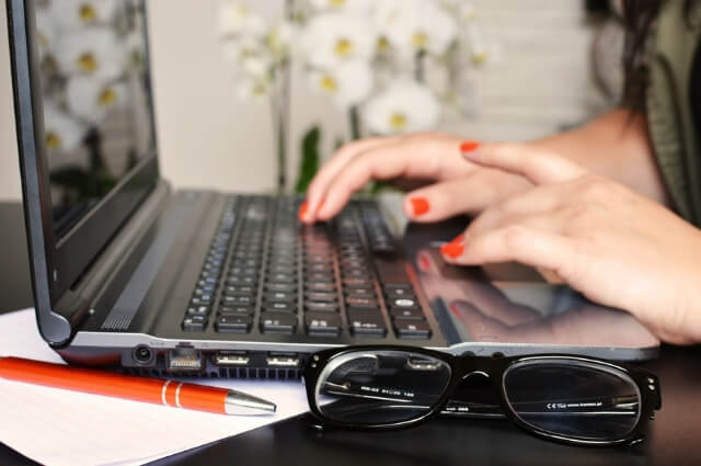 Image of a lady typing on her laptop writing a blog