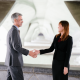 Photo of a man in a business suit and a lady in a business suite shaking hands in an office