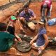 Picture of a man and children helping to build a school in Kenya