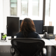 Picture of a female worker sitting at her desk starring at her computer looking bored