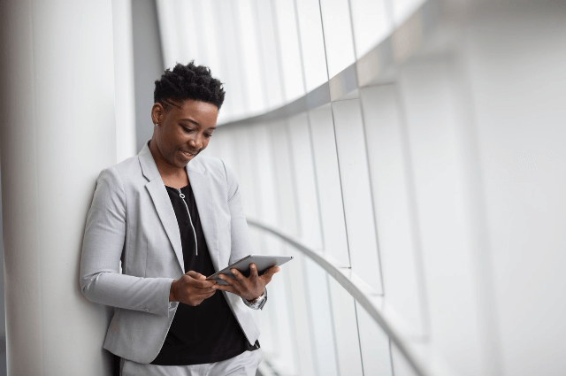 Photo of a business woman holding a tablet liaising with clients