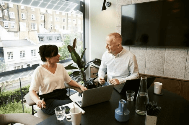 Image of two business people sharing workspace in a shared office