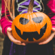 Picture of a girl dressed in as a witch holding a jack o lantern for Halloween
