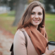 Image of a woman holding a take away coffee cup outside in the autumn