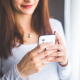 Picture of a woman smiling whilst holding a mobile phone