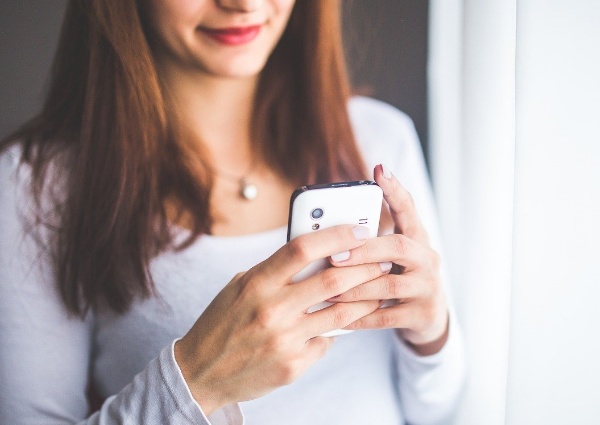 Picture of a woman smiling whilst holding a mobile phone