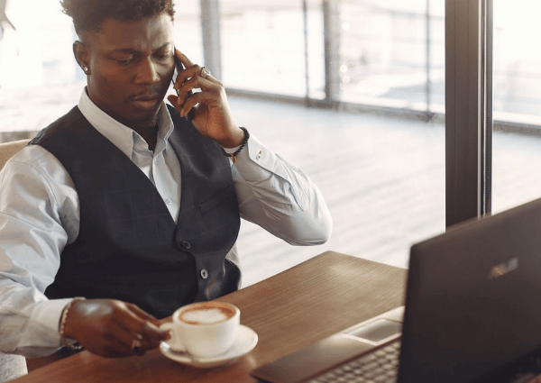 Picture of a man working from a serviced office with a laptop and a cup of tea whilst taking a call