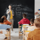 Image of a teacher standing at a blackboard teaching school children