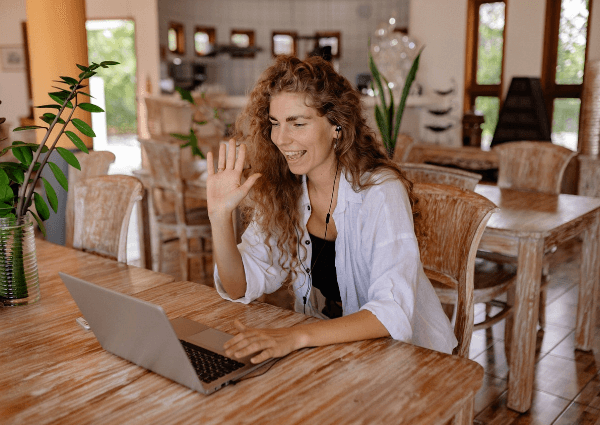 Picture of a woman smiling and waving on a networking video conferencing call