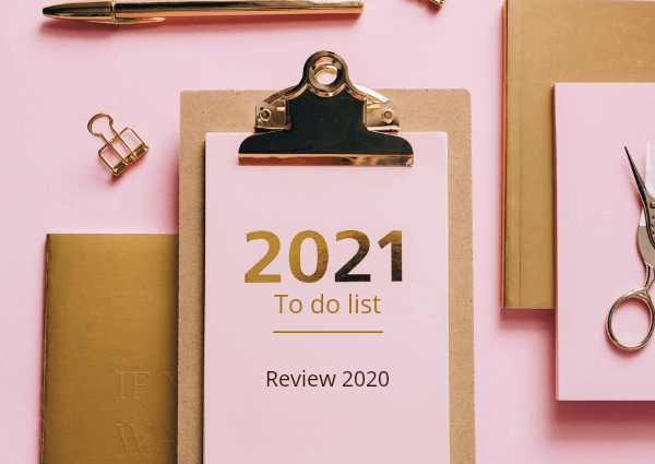 An image of a clipboard and office stationery on a pink background. The clipboard reads 2021 to do list review 2020