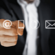 Image of a business man pointing at an email @ sign