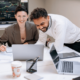 An image of a man and woman happily working together in a hybrid workplace