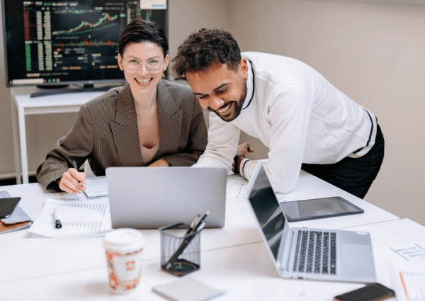 An image of a man and woman happily working together in a hybrid workplace