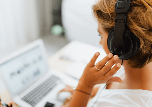 Small Business woman at her laptop wearing headphones answering customer queries