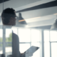 Image of a business man in an office holding a tablet working in natural sunlight