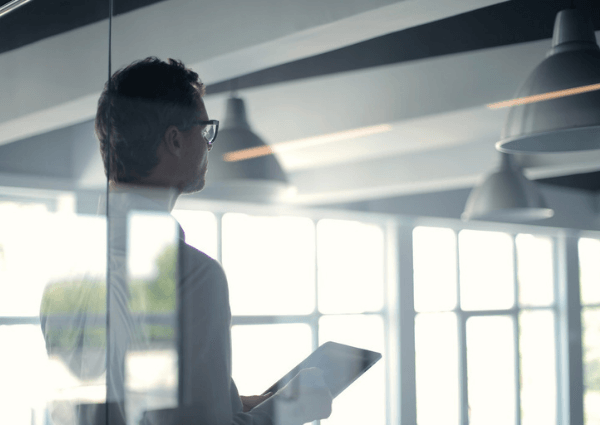 Image of a business man in an office holding a tablet working in natural sunlight