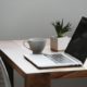 Image of a desk and a chair with a laptop and coffee set up for home working
