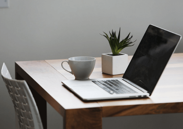 Image of a desk and a chair with a laptop and coffee set up for home working