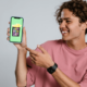 A customer holding and smiling at a phone having received a birthday treat from a business