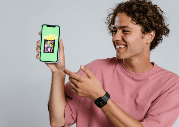 A customer holding and smiling at a phone having received a birthday treat from a business