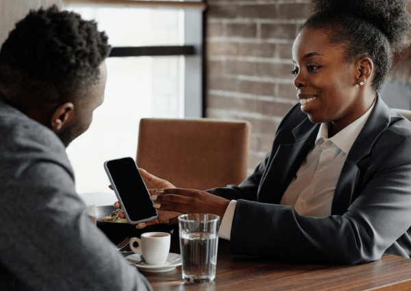 Business woman showing a digital business card on her phone to a customer