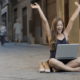 Picture of a business woman sitting on the floor of a road with her laptop