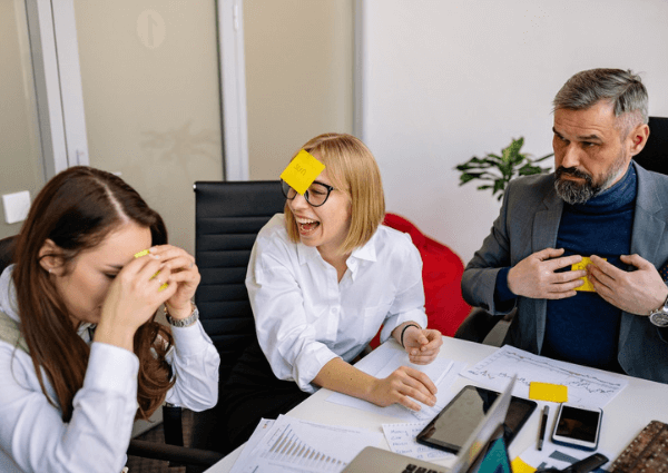 Colleagues at work playing a game with notes stuck to their foreheads