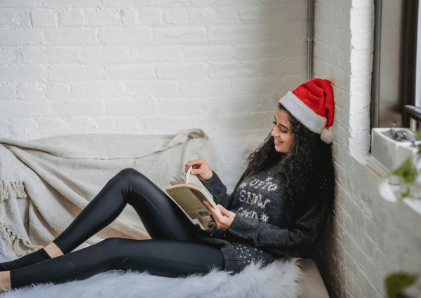 Image of a women relaxing reading a book in a santa hat