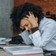 Business woman hunched over a desk of papers looking stressed