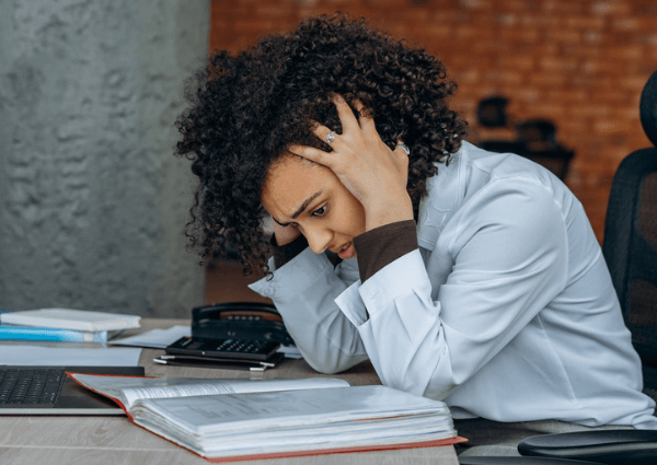 Business woman hunched over a desk of papers looking stressed