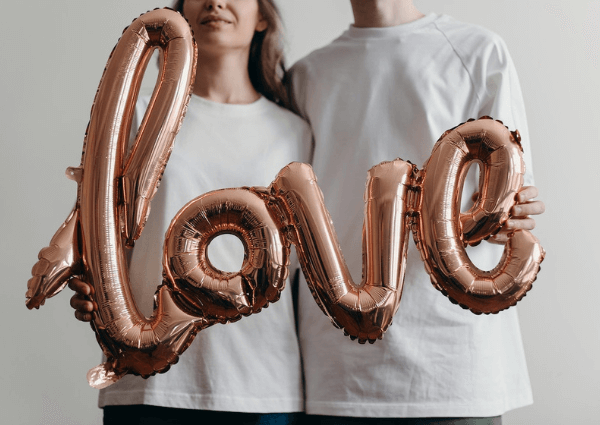 Picture of a man and a woman holding an inflated love balloon