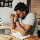 Image of a businessman sitting at a desk with a laptop looking tired