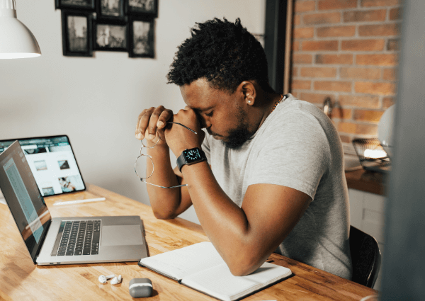 Image of a businessman sitting at a desk with a laptop looking tired