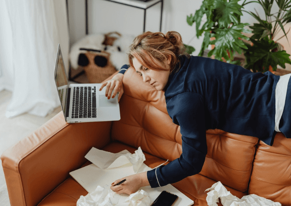 Picture of a female homeworker slouched on the couch with her laptop