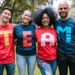 Four team members standing together wearing a t-shirt each with a letter that spells team