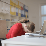 Business woman sitting at her laptop with her head on the desk