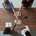 Picture of four business people locking hands across a table