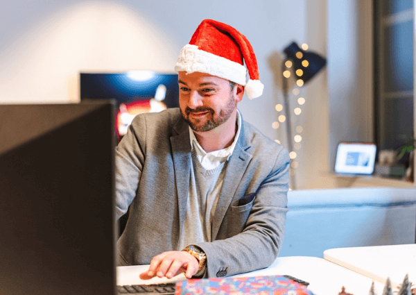 Picture of a man sitting at a computer in the office wearing a Christmas hat