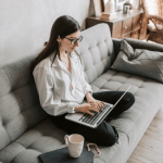 Women sitting on the sofa at home with her laptop on her knees