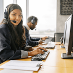 A woman sitting at her computer wearing headphones acting as a customer services agent