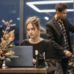 Picture of a business woman working in an office with a small Christmas tree on her desk