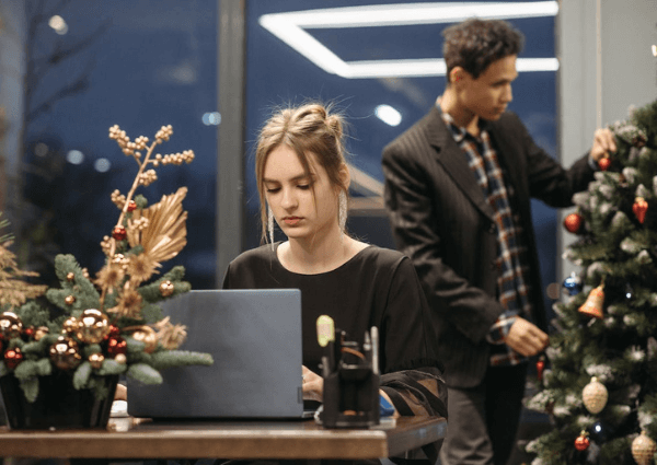 Picture of a business woman working in an office with a small Christmas tree on her desk