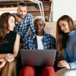 Three business owners sitting with a school child working on a laptop