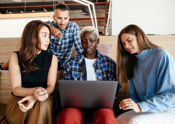 Three business owners sitting with a school child working on a laptop