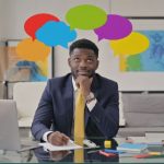 Business man sitting at his desk with speech bubbles above his head